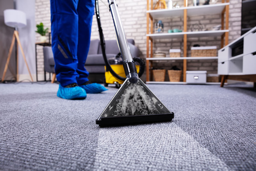 A man cleaning a carpet in a living room.
